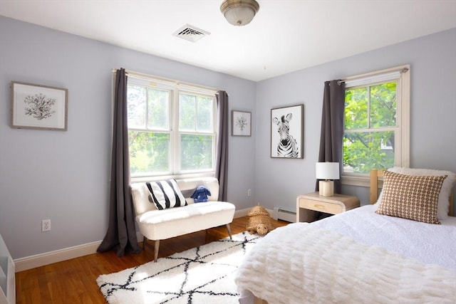 17-19 Beech Gln, Boston, MA 02119 - bedroom featuring a baseboard heating unit, multiple windows, baseboards, and wood finished floors