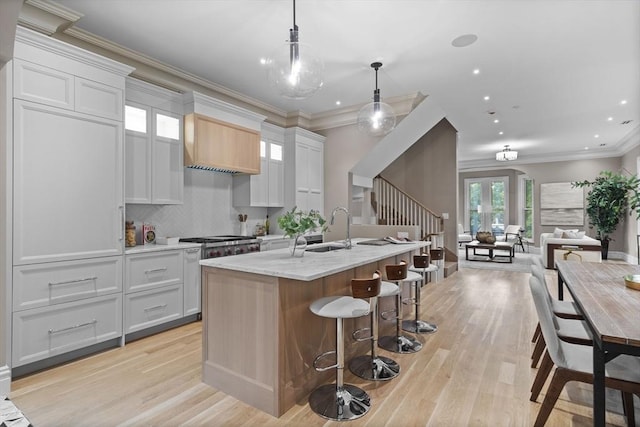 17 Alveston St, Boston, MA 02130 - kitchen featuring a sink, open floor plan, an island with sink, light wood-style flooring, and a breakfast bar area
