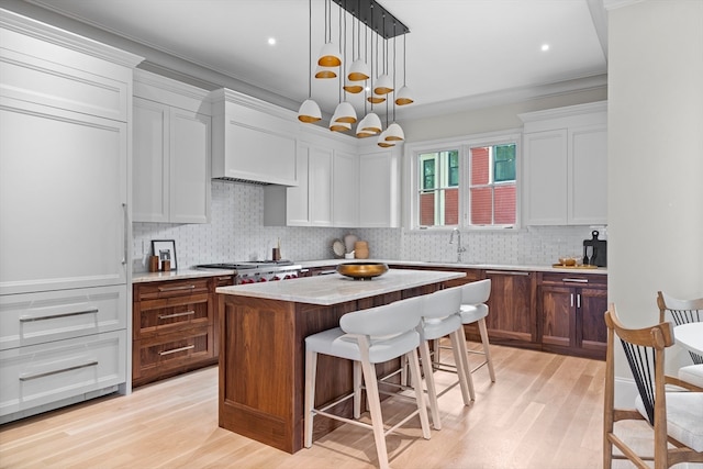 kitchen with light hardwood / wood-style flooring, pendant lighting, a center island, and white cabinets