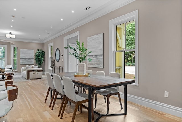 dining area with crown molding and light hardwood / wood-style floors