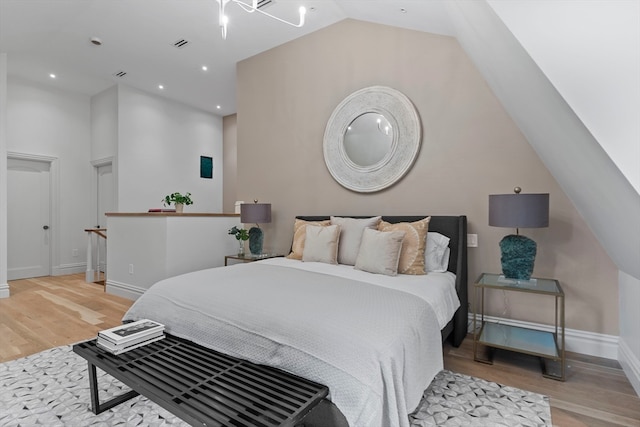 bedroom with vaulted ceiling and light hardwood / wood-style flooring