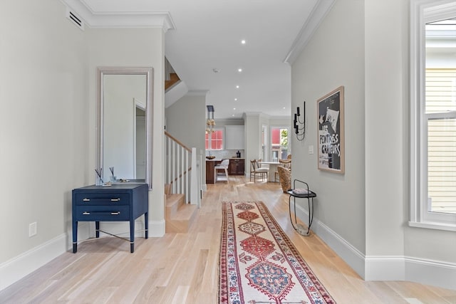 hallway featuring ornamental molding, plenty of natural light, and light hardwood / wood-style floors