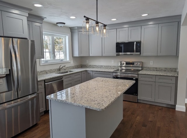 kitchen featuring sink, a center island, stainless steel appliances, pendant lighting, and dark wood-type flooring