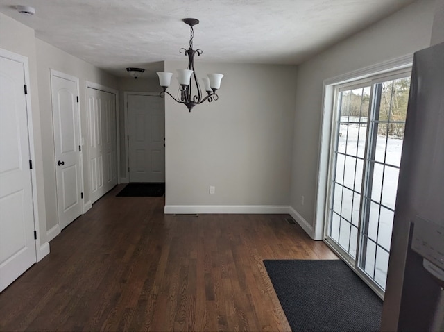 unfurnished dining area with a chandelier and dark hardwood / wood-style floors