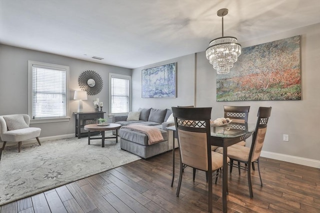 dining room with a notable chandelier, baseboards, visible vents, and dark wood-style flooring