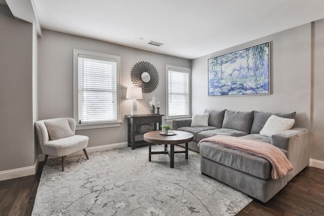 living area featuring baseboards, plenty of natural light, visible vents, and wood finished floors