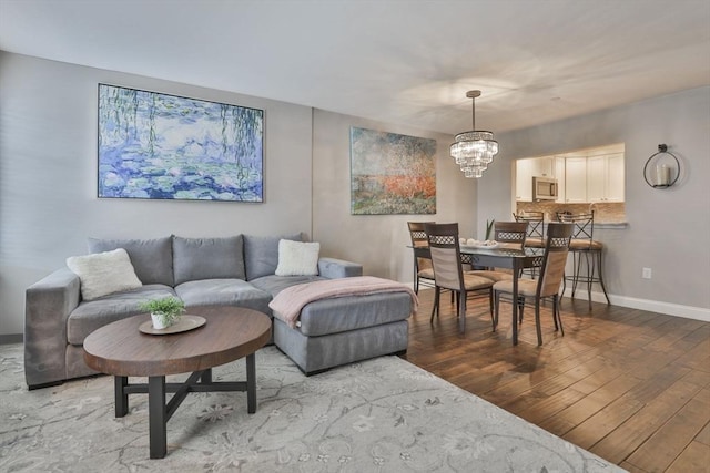 living area featuring baseboards, wood finished floors, and a notable chandelier