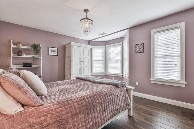 bedroom with a notable chandelier, multiple windows, dark wood finished floors, and baseboards