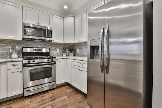 kitchen with stainless steel appliances, dark wood-type flooring, backsplash, and white cabinetry