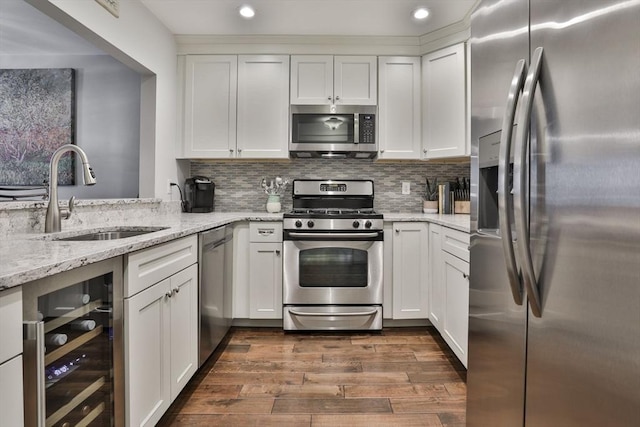 kitchen with wine cooler, dark wood-style flooring, backsplash, appliances with stainless steel finishes, and a sink