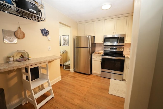 kitchen featuring appliances with stainless steel finishes, light wood-type flooring, white cabinets, and light countertops