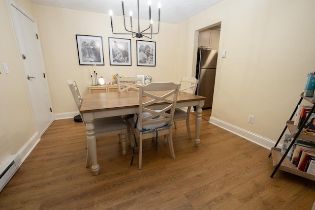 dining area with a chandelier, wood finished floors, baseboards, and a baseboard radiator