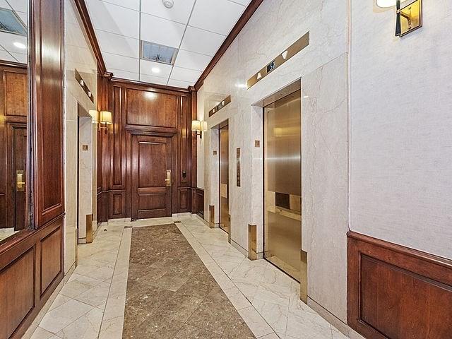 2 Hawthorne Pl Unit 2E & 2F, Boston, MA 02114 - hallway with elevator, ornamental molding, light marble finish flooring, and wood walls