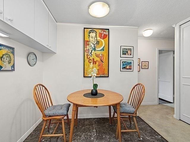 2 Hawthorne Pl Unit 2E & 2F, Boston, MA 02114 - dining room featuring baseboards, a textured ceiling, and crown molding