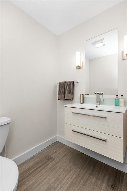 bathroom featuring toilet, wood finished floors, vanity, and baseboards
