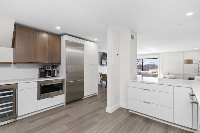 kitchen featuring wine cooler, light countertops, built in appliances, and modern cabinets