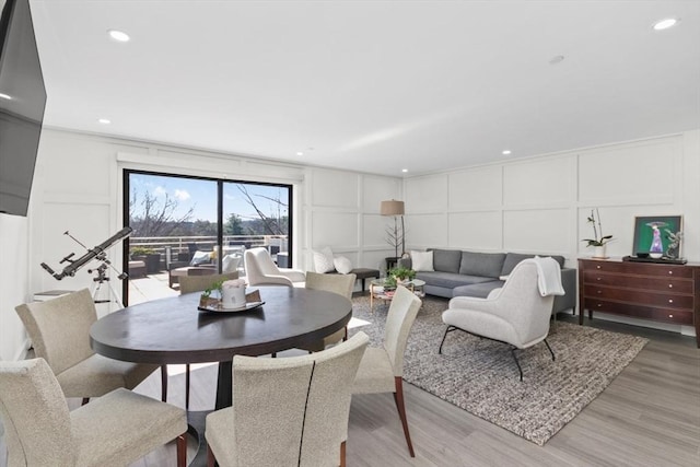 dining room featuring a decorative wall, light wood-style flooring, and recessed lighting