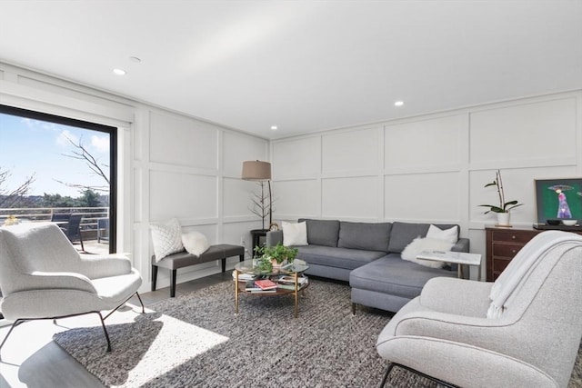 living area with a decorative wall, wood finished floors, and recessed lighting