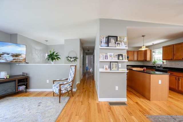 89 Block St, Abington, MA 02351 - kitchen featuring light wood-style flooring, brown cabinetry, decorative light fixtures, dark countertops, and a sink
