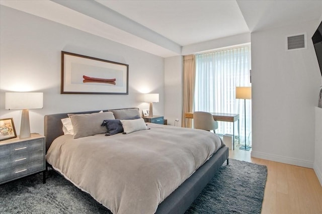 bedroom featuring visible vents, baseboards, and wood finished floors