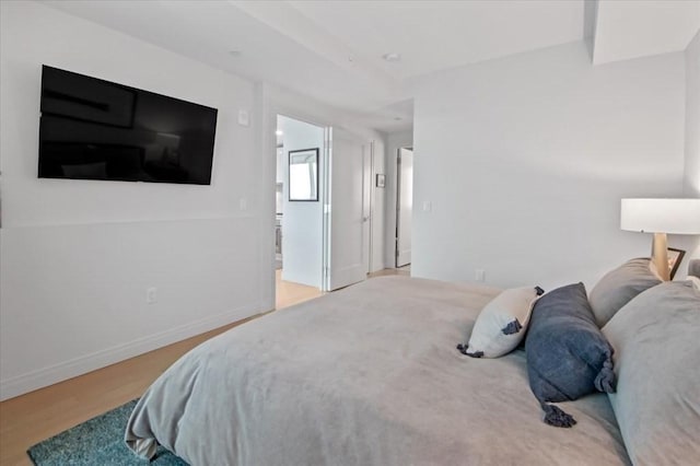 bedroom with baseboards, wood finished floors, and ensuite bathroom