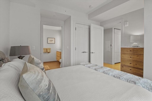 bedroom with a closet, light wood-type flooring, and ensuite bathroom