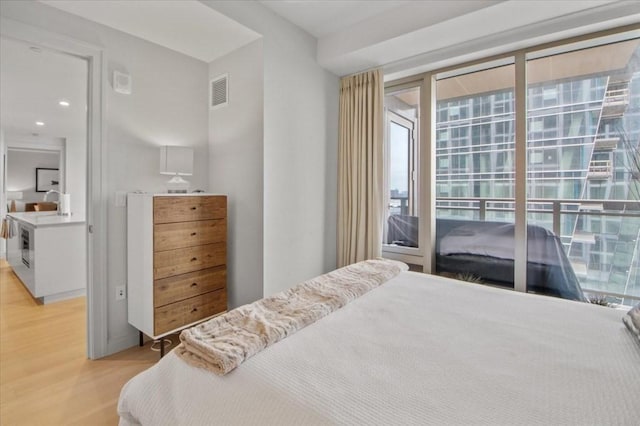 bedroom with light wood-type flooring, visible vents, and access to exterior