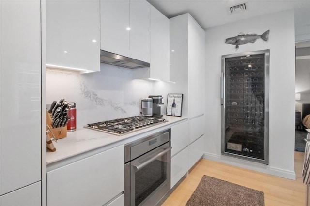 kitchen featuring white cabinetry, modern cabinets, under cabinet range hood, and stainless steel appliances