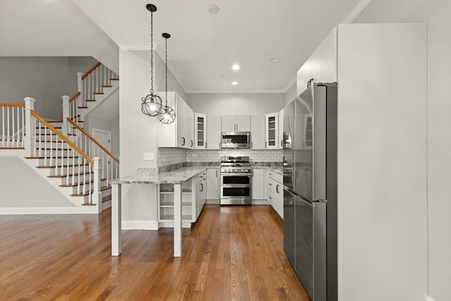 kitchen with appliances with stainless steel finishes, light stone countertops, white cabinetry, decorative light fixtures, and backsplash