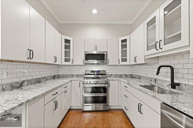 kitchen featuring sink, white cabinetry, light stone counters, backsplash, and appliances with stainless steel finishes