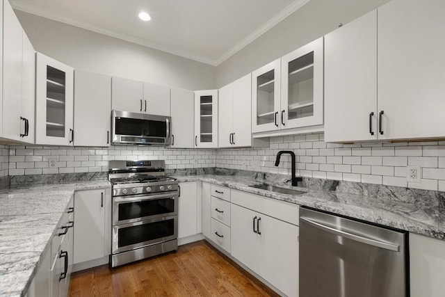 kitchen with stainless steel appliances, sink, white cabinets, light stone counters, and backsplash