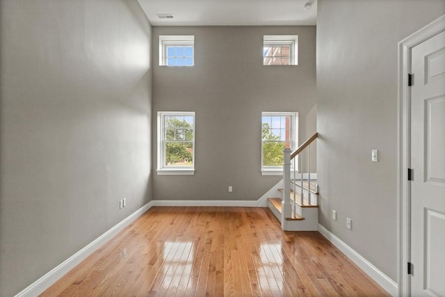 unfurnished living room with a high ceiling and light wood-type flooring