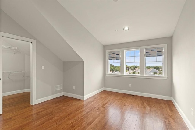 additional living space with vaulted ceiling and light hardwood / wood-style floors