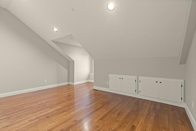 additional living space featuring light hardwood / wood-style flooring and vaulted ceiling