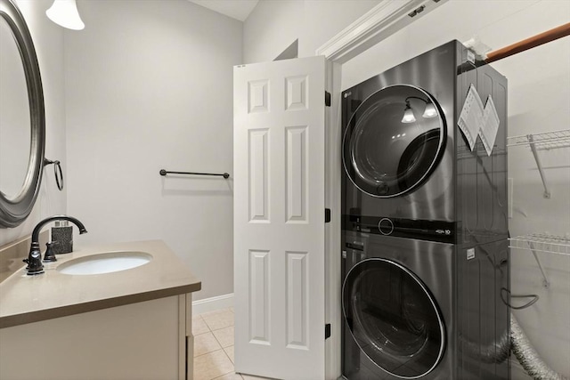 laundry area with sink, light tile patterned floors, and stacked washer and dryer