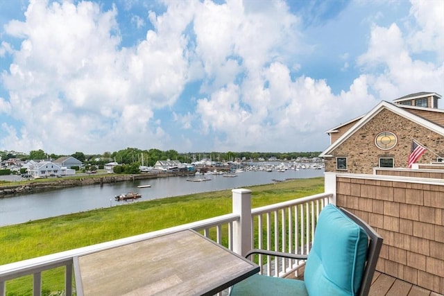 wooden terrace featuring a water view and a lawn