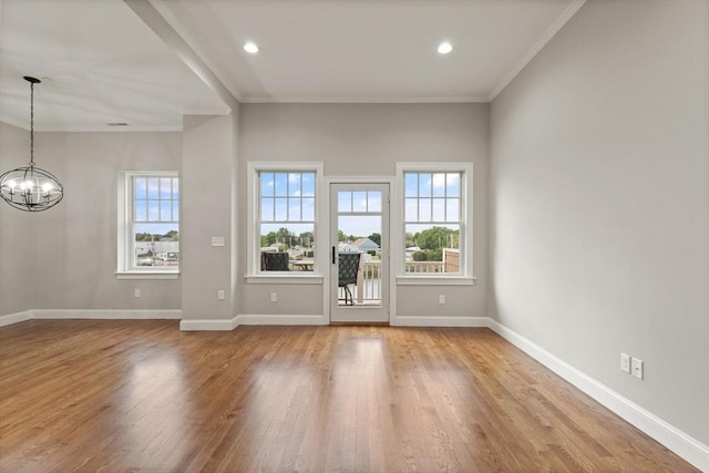 unfurnished living room with crown molding, light hardwood / wood-style floors, and a notable chandelier