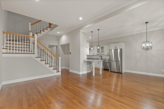 unfurnished living room featuring a notable chandelier, light hardwood / wood-style floors, and crown molding