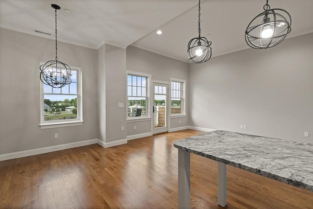 unfurnished dining area featuring an inviting chandelier, crown molding, and wood-type flooring