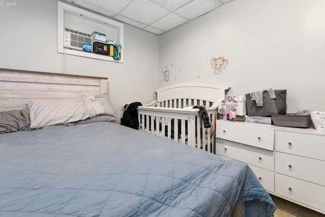 bedroom featuring a drop ceiling and wood finished floors