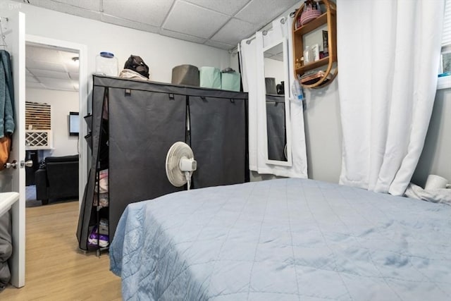 bedroom featuring light wood-type flooring and a drop ceiling