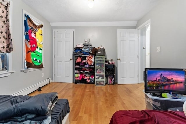interior space featuring a baseboard heating unit, wood finished floors, and a textured ceiling