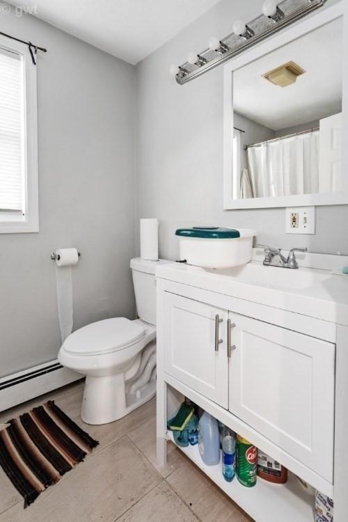 full bathroom featuring vanity, a baseboard radiator, visible vents, and toilet