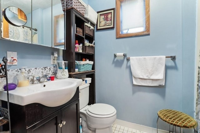 bathroom featuring tile patterned floors, vanity, baseboards, and toilet