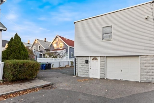 garage with fence and aphalt driveway