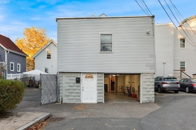 rear view of property with driveway, fence, and a garage