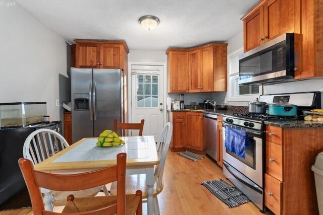 kitchen featuring light wood-style floors, brown cabinets, a sink, and appliances with stainless steel finishes