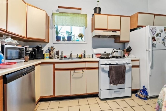 kitchen featuring light tile patterned floors, light countertops, under cabinet range hood, appliances with stainless steel finishes, and a sink