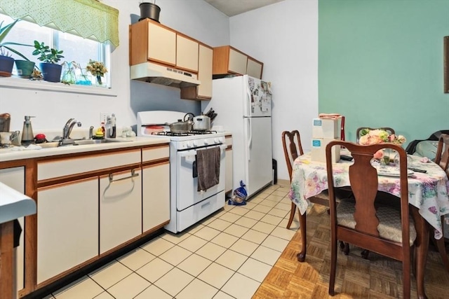 kitchen featuring white appliances, light countertops, light tile patterned flooring, under cabinet range hood, and a sink