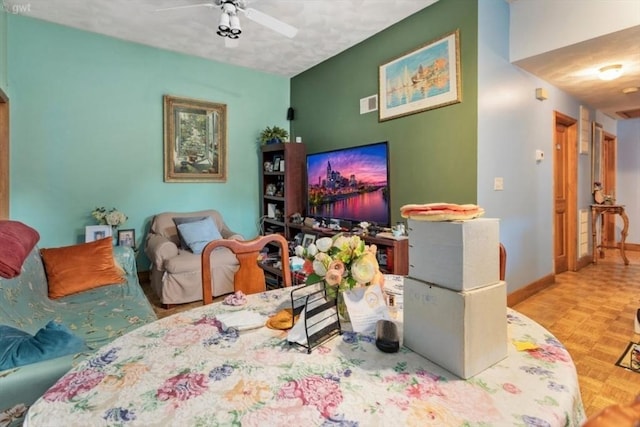 living area with baseboards and a ceiling fan
